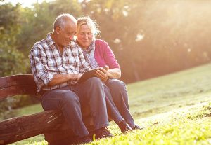 senior man and woman sitting on a bench looking at a mobile-friendly website on a tablet